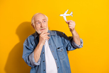 Photo of serious focused man arm on chin look interested little paper plane isolated on yellow...