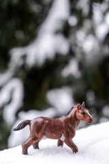 small plastic toy horse outside in the snow
