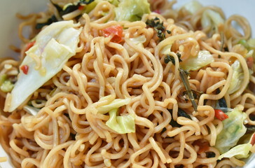 spicy fried instant noodles with cabbage and basil leaf on plate