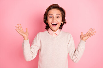 Portrait of attractive cheerful pre-teen guy having fun good news isolated over pink pastel color...
