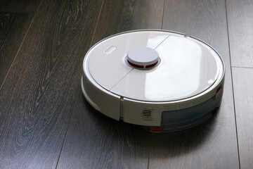 Smart Robot vacuum cleaner cleaning a living room with woman lifting her feet to create path way for the device