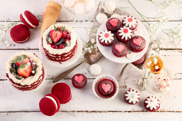 Delicious cake and cupcakes in red on white background. Table setting for celebration.
