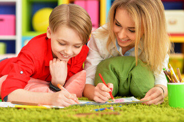 Fototapeta premium Close up view of smiling mother and son drawing with pencils