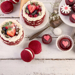 Delicious cake and cupcakes in red on white background. Table setting for celebration.