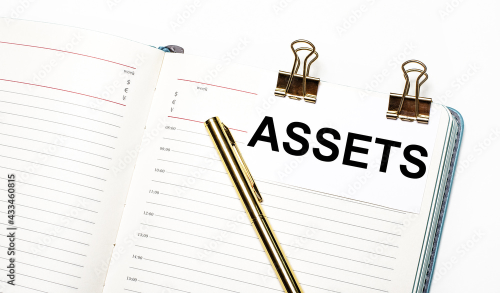 Poster on a light background, an open notebook, a sheet of paper with gold clips and the text assets and a 