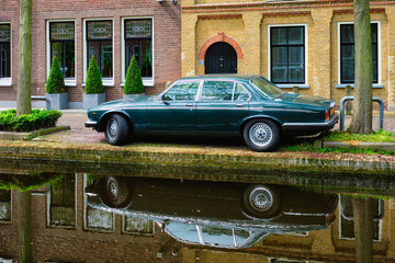 Old car on canal embankment in street of Delft. Delft, Netherlands