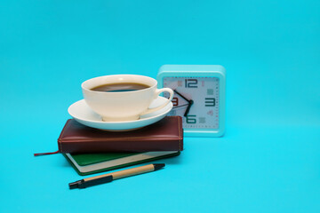 A cup of coffee, a watch, and a notebook on a blue background. The concept of the business theme.