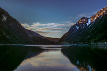 The mountains reflecting in the lake of Poschiavo in Switzerland during a colorful Sunset