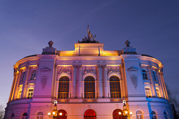 The main building of Warsaw University of Technology at dusk lit by colorful lights. Warsaw, Poland.