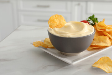 Potato chips and mayonnaise on white marble table, space for text