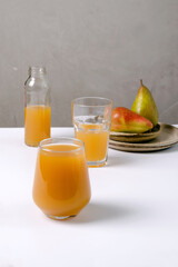 Useful, natural fruit juice in a glass on a white and gray background. The concept of dietary nutrition, copying space, selective focus, minimalism