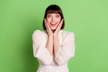 Photo of young excited girl happy positive smile hands touch cheeks surprised isolated over green color background