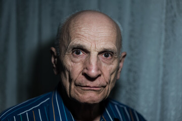 Closeup portrait of senior bald man with dark shadow behind head.