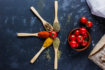 spoons with spices, paprika, basilic, pepper, thyme with cherry tomatoes