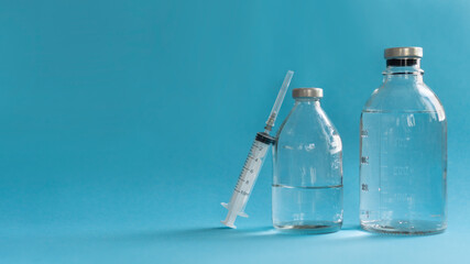 medicine concept, syringe and glass vial with medicine for injection saline dehydration rinsing close-up, blue background with copy space