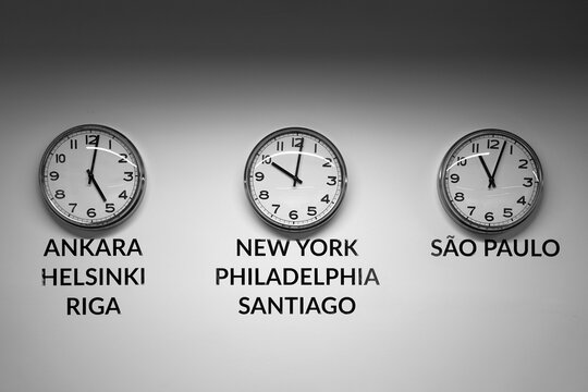 Many wall clocks on the white wall of business office showing time of different cities of the world