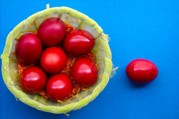 red painted eggs for Easter in a basket, on blue background. top view. selective focus