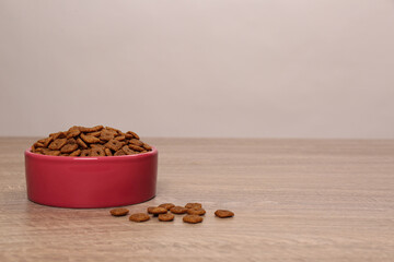 Dry food in pet bowl on wooden surface, space for text