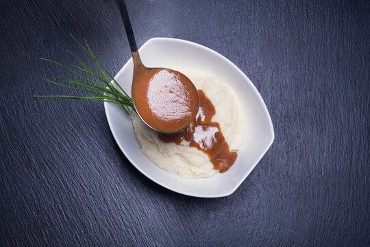 Mashed potatoes with gravy on blackstone background. Dark food photography. Concept of gourmet food