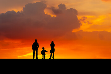Obraz na płótnie Canvas Silhouette of father, mother and daughter walking on the outdoor at dusk, Happy family together, parents with their little child at sunset