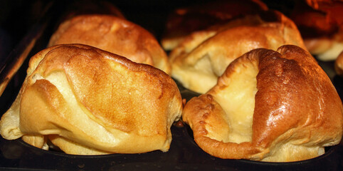 golden cooked roasted Yorkshire puddings in a oven tray for the traditional British Sunday lunch.