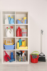 Shelving unit with detergents and cleaning tools near white wall indoors