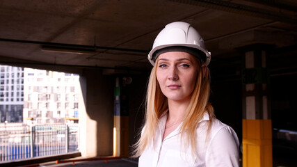 portrait of a young beautiful woman builder in a white construction helmet. Young girl engineer at a construction site.