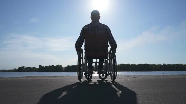 A man in a wheelchair walks on the waterfront