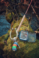 Fly box and rod on the river bank. Fly fishing.