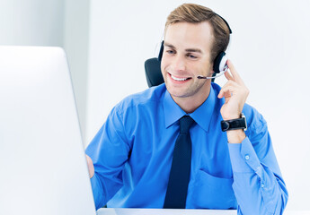 Portrait of happy smiling support phone male operator in headset, blue shirt and tie, with...