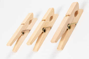 three wooden clothespins with a metal spring on the background of a white wooden table. close-up. selective focus