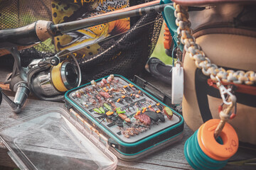 Fly box and rod on the river bank. Fly fishing.