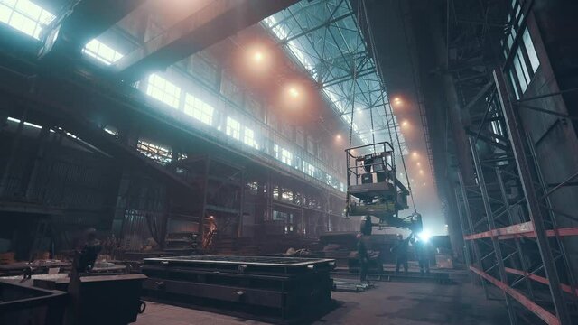 Interior of large foundry steel workshop with cast iron products, workers and beam crane, heavy metallurgy industry.