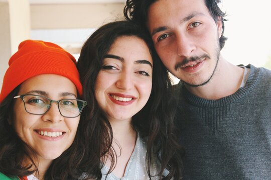 three young friends of turkish ethnicity looking at camera smiling at outdoors home balcony, horizontal image