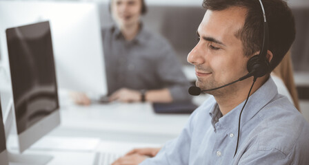Obraz premium Call center. Group of casual dressed operators at work. Adult businessman in headset at customer service office. Telesales in business