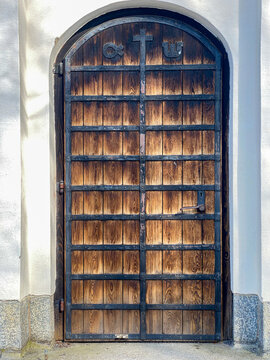 Outdoor front view of beautiful old wooden door entrance with black iron fittings and white stone building.