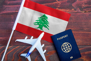 Flag of Lebanon with passport and toy airplane on wooden background. Flight travel concept.
