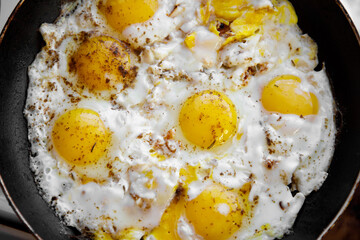 Scrambled eggs with spices are cooked in a skillet.