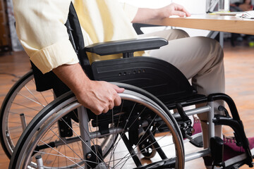 partial view of young man sitting in wheelchair at home