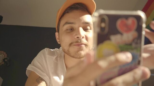 Hombre Joven gay con gorra naranja conversa por videollamada 
