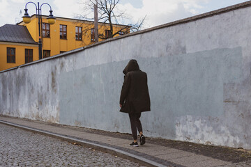 man in a hooded black jacket walking on the street