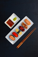 The sushi set is a famous Japanese dish, put on a ceramic plate, beautifully arranged on a black...
