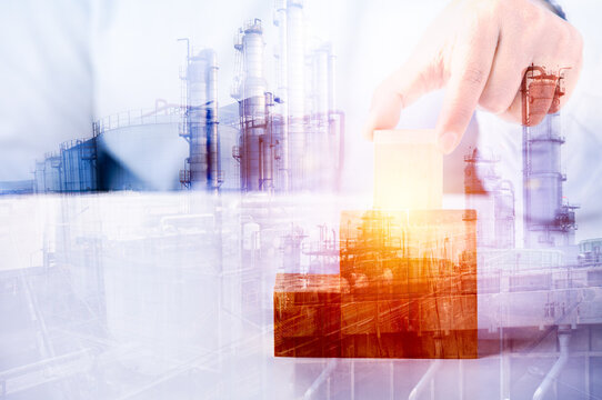 Double exposure image concept, hand holding wooden block idea business industrial technology future plant and enegry graphic design. Oil, gas and petrochemical refinery factory with background.