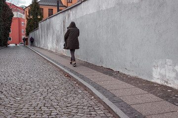 man in a hooded black jacket walking on the street