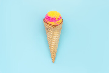 Sweet yellow pink fruit ice-cream sorbet in a waffle cone with banana and strawberry flavor isolated on a color light blue background. Copy space for text or design. Summer concept
