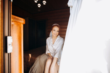 Boudoir Bride's morning. Cute red-haired girl in her wedding day.  Luxurious bride in a beautiful satin robe