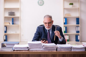 Old businessman employee unhappy with excessive work in the office