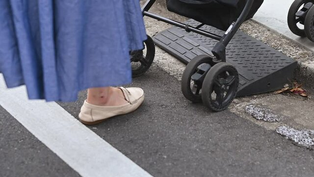 段差をベビーカーで上がるお母さん
