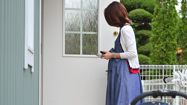 家のドアの鍵を開ける妊婦のお母さん