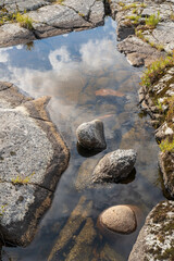 Clear clear water with a reflection of blue sky and clouds in the rock. 